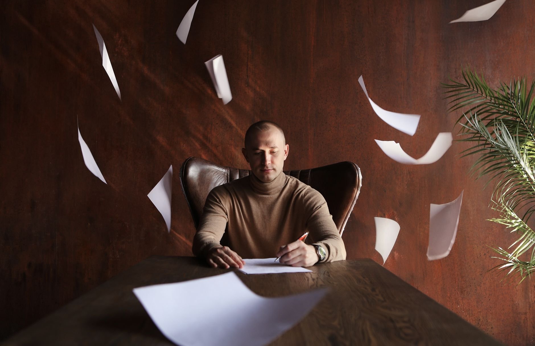 Businessman working at desk amidst papers, suggesting creativity and focused problem-solving.