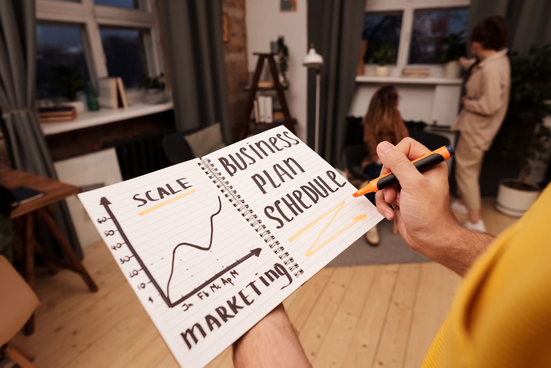 Person holding a notebook with planning details and business strategy graph.